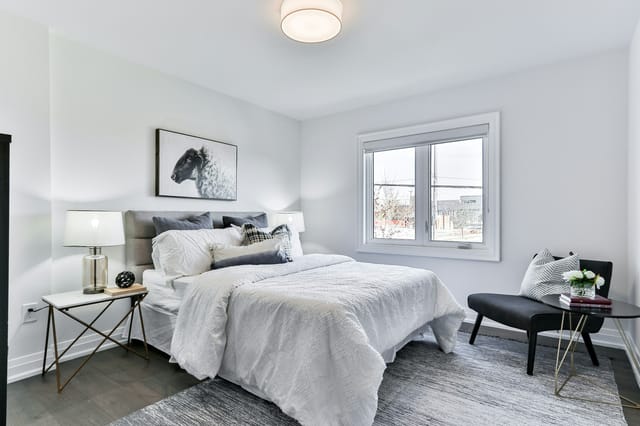 Chambre blanche avec lit double, deux fenêtres et bureau