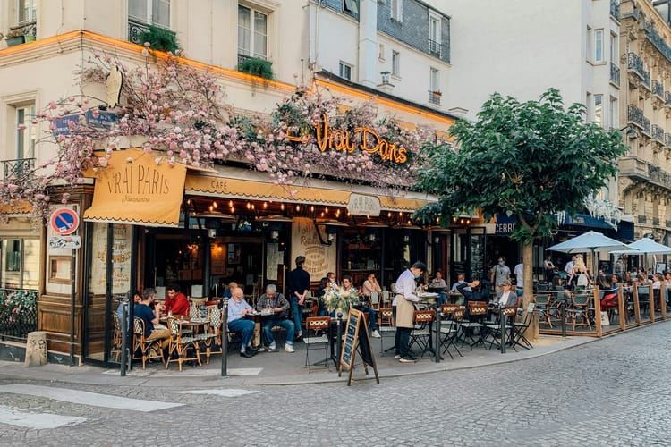 Terrasse de café animée à l’angle de deux rues parisiennes